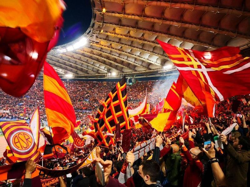 AS Roma supporters waving red and yellow flags inside Stadio Olimpico.